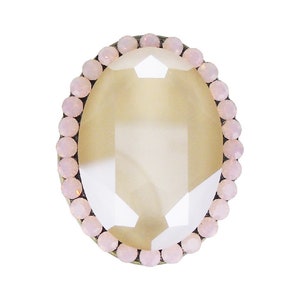 May include: A large, oval-shaped, clear glass ring with a pink crystal border.
