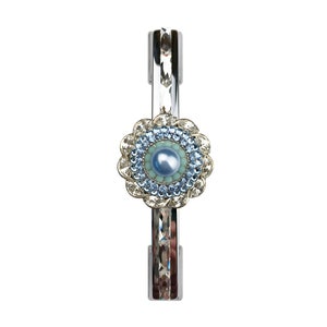 Può includere: Un braccialetto rigido in argento con un design a fiore blu e bianco. Il fiore ha una perla al centro ed è circondato da strass trasparenti.