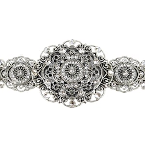 Op de afbeelding: Zilverkleurige haarspeld met een sierlijk filigraanontwerp. De haarspeld heeft drie ovale secties, elk versierd met sprankelende, heldere kristallen. De centrale sectie is de grootste, met een cirkelvormig patroon van kristallen.
