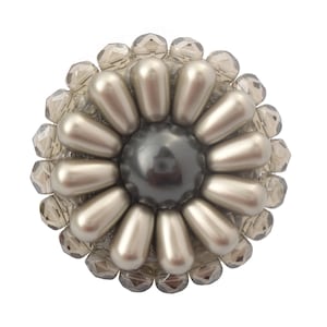 Puede incluir: Un broche de flor de cuentas plateadas y grises con una gran perla gris en el centro.