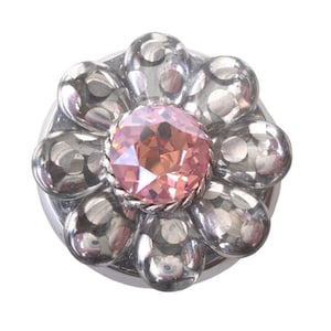 Puede incluir: Un botón de plata con forma de flor con un strass rosa en el centro.