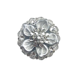 以下が含まれることがあります： 黒いハンドルと「But First, Coffee」のテキストが黒い太字で書かれた白いセラミックマグ。マグは白い表面に置かれています。