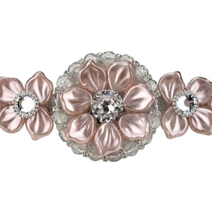 Peut inclure: Une broche de fleur rose avec trois fleurs et des strass clairs au centre de chaque fleur.