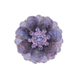 以下が含まれることがあります： 中央に大きな透明なクリスタル、周囲に小さな紫色のクリスタルが散りばめられた、紫色の花の形をしたブローチです。