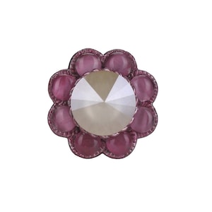 May include: A pink flower-shaped button with a clear, faceted crystal in the centre.