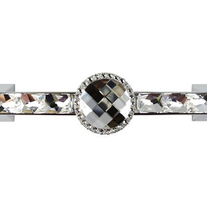 May include: A silver cabinet pull with a large, faceted crystal knob surrounded by smaller crystals. The pull is rectangular and has a silver finish.