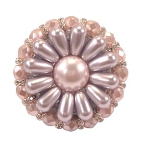 以下が含まれることがあります： 中央に大きな真珠がついた、丸いピンクとシルバーの花の形をしたブローチ。ブローチは、小さな真珠とラインストーンで囲まれています。