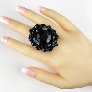 May include: A large black ring with a large black gemstone surrounded by smaller black gemstones.