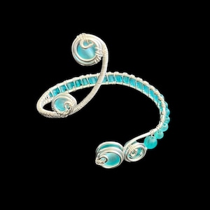 May include: A silver wire wrapped bracelet with turquoise blue glass beads and larger turquoise blue glass stones.