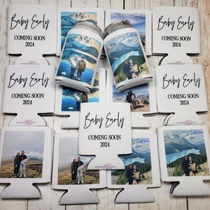 May include: White can coolers with the text "Baby Early COMING SOON 2024" in black script. Some coolers hold cans with scenic photos. The coolers are designed to keep beverages cold.