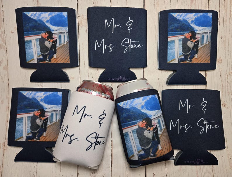 May include: Navy blue can coolers with a photo of a couple and the text "Mr. & Mrs. Stone." Some coolers are shaped like computer monitors. One cooler is white with black text. The photo shows a couple on a deck with a mountain and water background.