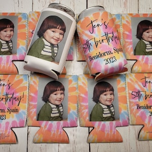 May include: A collection of personalized can coolers with a tie-dye background in shades of pink, orange, and blue. Each cooler features a photo of a person and the text "Jen's 50th birthday! Benidorm, Spain 2023."