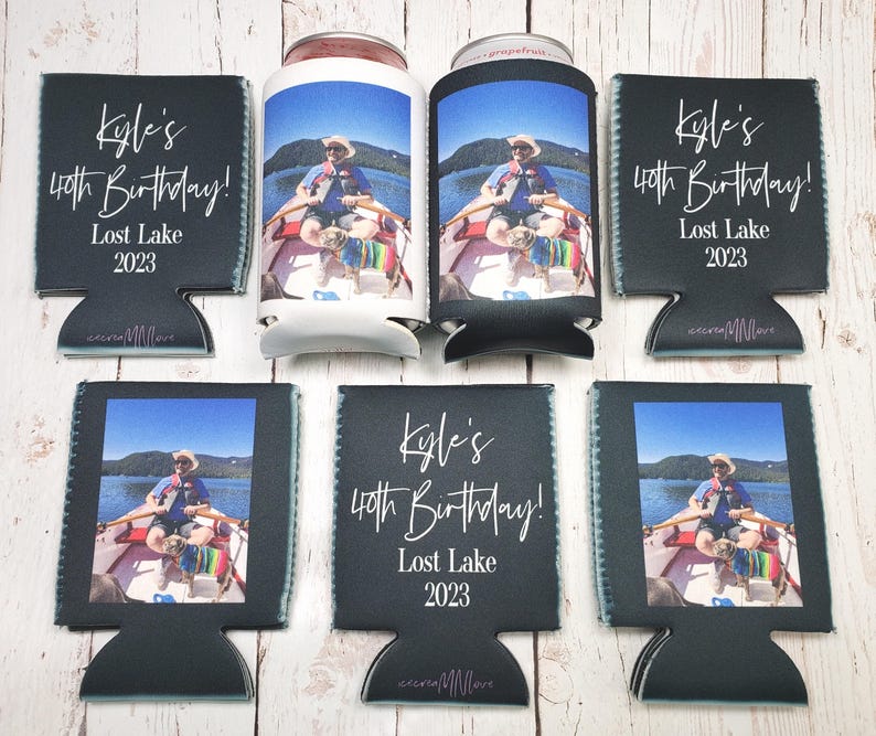May include: A collection of black can coolers and two cans. The coolers feature a photo of a person in a boat on a lake, with the text "Kyle's 40th Birthday! Lost Lake 2023". The coolers are made of a neoprene-like material.