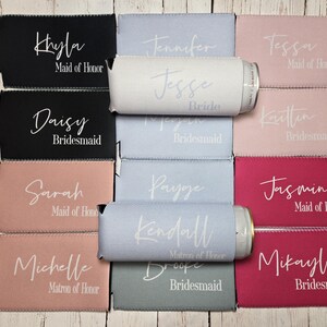 May include: Set of ten personalised can coolers in various colours, including black, pink, and blue. Each cooler features a name and title, such as "Maid of Honour" or "Bridesmaid".