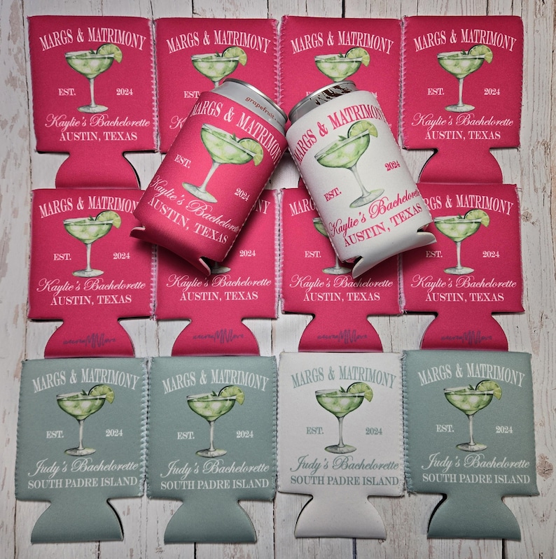 May include: A collection of drink koozies and a can, featuring a margarita design with the text "MARGS & MATRIMONY" and "Kaylie's Bachelorette Austin, Texas" or "Judy's Bachelorette South Padre Island". The koozies are pink, light blue, and white.