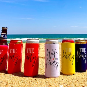 May include: Six colorful can coolers with different text on them. The coolers are on a sandy beach with a blue ocean and sky in the background. The text on the coolers reads "The Party", "Wife of the Party", and "The Party".