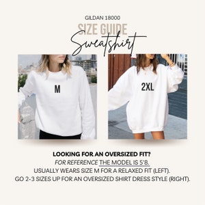 May include: White Gildan 18000 sweatshirt size guide. The image shows two models wearing white sweatshirts, one labeled "M" and the other "2XL". Text provides sizing information for a relaxed or oversized fit. The model is 5'8.