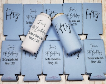 May include: A set of blue and white can coolers with the text "Fifty" and "Jean's 50th Birthday" printed on them. The coolers are designed to keep drinks cold.