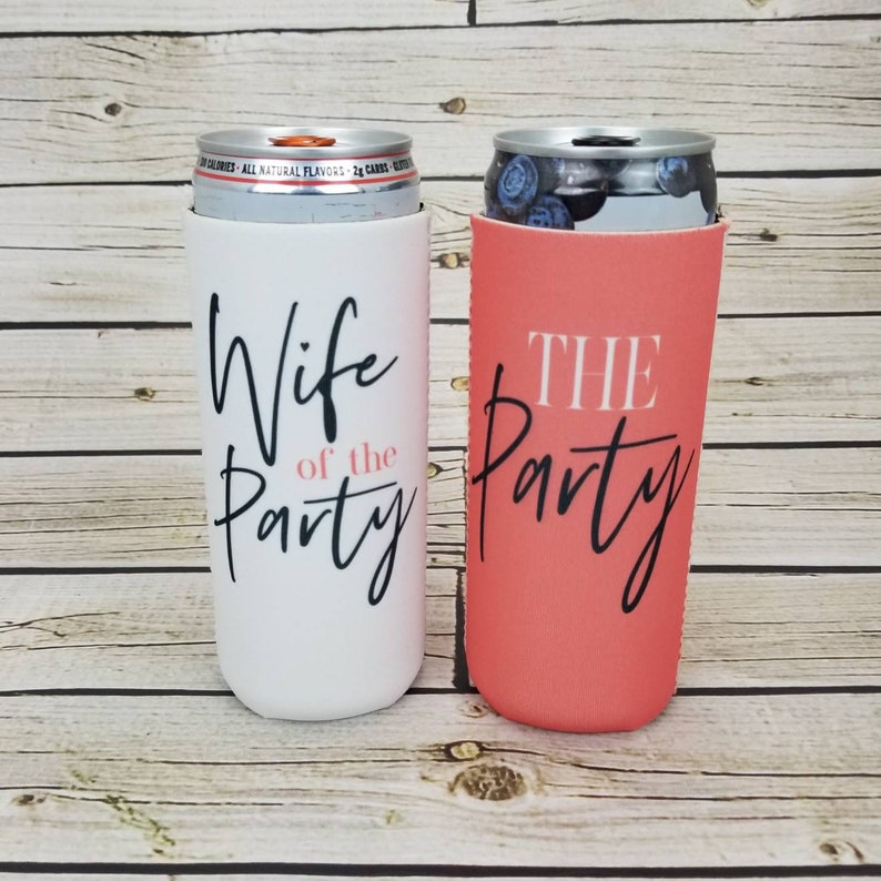 May include: Two white and coral can coolers with black text. The white cooler says "Wife of the Party" and the coral cooler says "The Party".