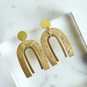 May include: A pair of gold-toned earrings with a brushed finish. Each earring features a double arch design.