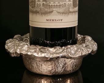 May include: A silver metal wine bottle holder shaped like a bunch of grapes. The holder is designed to hold a bottle of wine upright. The bottle is not included.