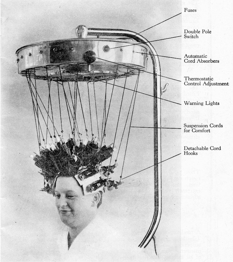 May include: A black and white image of a hair dryer with a silver metal frame and a black handle. The hair dryer has a round, silver metal top with a light bulb in the center. The hair dryer is attached to a silver metal stand with a black handle. The hair dryer is being used on a person's head. The hair dryer has a number of cords hanging from the top. The cords are labeled with the following text: 'Fuses', 'Double Pole Switch', 'Automatic Cord Absorbers', 'Thermostatic Control Adjustment', 'Warning Lights', 'Suspension Cords for Comfort', and 'Detachable Cord Hooks'.