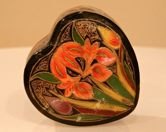 May include: A heart-shaped wooden box with a hand-painted design of flowers in shades of orange, yellow, and green on a black background.