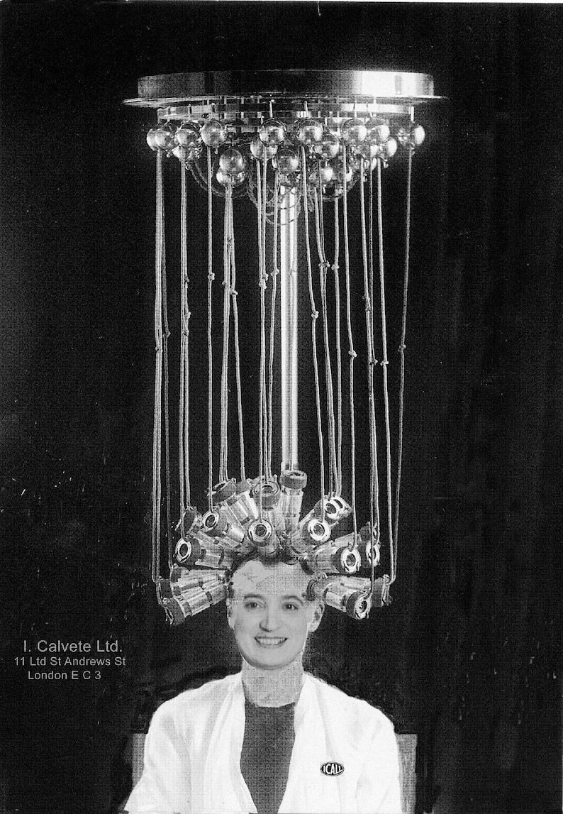 May include: A woman with her hair in curlers under a metal hair dryer with multiple bulbs. The hair dryer is suspended from the ceiling. The woman is wearing a white lab coat with a black badge that says 'ICAL'.