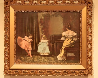 May include: A framed vintage print of a woman playing a piano with two young girls in a room with a dark brown wall and a patterned rug. The woman is wearing a yellow dress with a white lace collar and the girls are wearing pink and blue dresses.