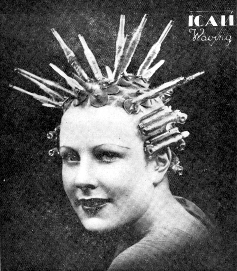 May include: A black and white photo of a woman with her hair in curlers. The curlers are made of metal and have a long, thin shape. The woman is looking at the camera with a smile. The text 'ICAII Waving' is visible in the upper right corner of the image.
