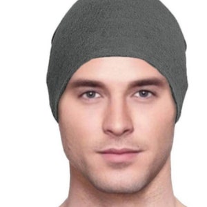 May include: A gray beanie made of a soft, textured fabric. The beanie is pulled down over the forehead and covers the ears.