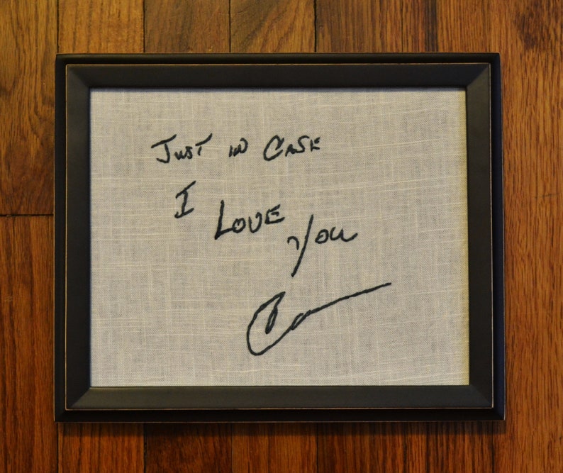 May include: A framed piece of fabric with the handwritten message "Just in case I love you" and a signature.