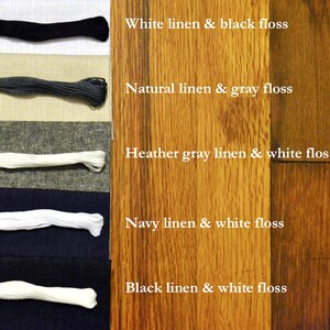 May include: Five swatches of linen fabric paired with matching floss thread. The linen swatches are white, natural, heather gray, navy, and black. The floss thread is black, gray, white, white, and white.