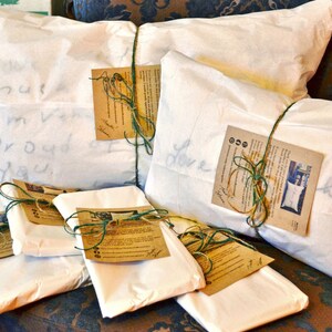 May include: Six white pillowcases wrapped in brown paper with green twine and a handwritten note on each. The notes say "Love", "I'm very proud of you", and "Must be a good girl".