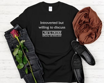 May include: Black t-shirt with white text that reads "Introverted but willing to discuss LAW & ORDER SPECIAL VICTIMS UNIT".