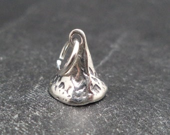 May include: Silver charm shaped like a chocolate kiss candy. The charm has a detailed design and a loop for attaching to a bracelet or necklace.