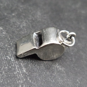 May include: A silver whistle charm with a loop for attaching to a necklace or bracelet.