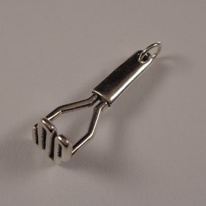 May include: Silver charm in the shape of a potato masher.