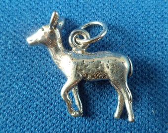 May include: A silver charm in the shape of a deer. The deer is standing on all four legs and has a small loop at the top for attaching to a bracelet or necklace.