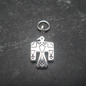 May include: Silver charm featuring a stylised Native American eagle design. The charm is detailed with geometric patterns and is suitable for jewellery making.