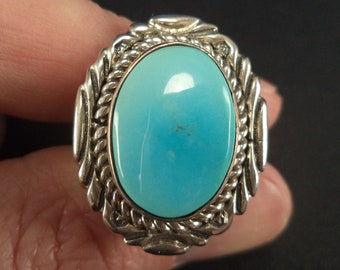 May include: A silver ring with a turquoise stone set in a rope-like design.