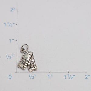 Puede incluir: Encanto de plata en forma de dos talones de entradas de cine. Cada entrada dice "ADMIT ONE". El encanto mide aproximadamente 1,25 cm de alto.