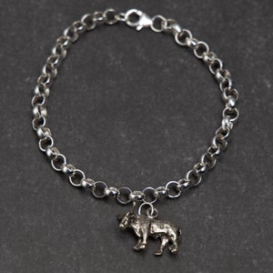 Puede incluir: Un brazalete de cadena de plata con un dije de toro de plata. El brazalete est&aacute; hecho de peque&ntilde;os eslabones redondos y tiene un cierre de langosta.
