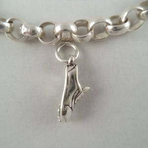 May include: A silver charm bracelet with a silver shoe charm. The bracelet is made of a chain with oval links.