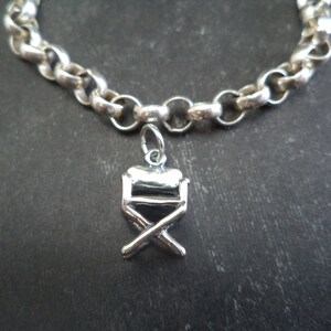 May include: A silver chain bracelet with a silver director's chair charm.