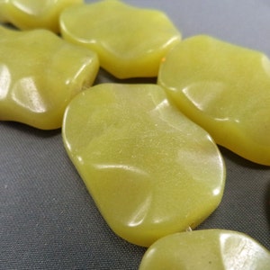 May include: A strand of yellow jade beads, each bead is irregularly shaped and has a smooth, polished surface.