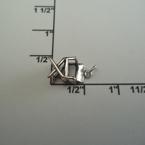 May include: A silver charm in the shape of a folding chair. The charm is approximately 1.25 cm tall and 1.25 cm wide. It is a great addition to any charm bracelet.