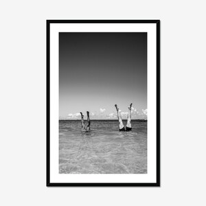 Black and white coastal beach photo print in sleek black frame, vertical wall art styled against white wall for beach cottage decor.