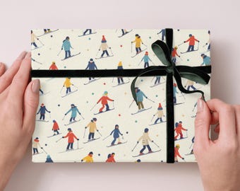 May include: A rectangular gift box wrapped in cream-colored paper featuring a repeating pattern of stylized skiers in various colorful winter outfits, tied with a dark green velvet ribbon tied in a bow across the center of the package.