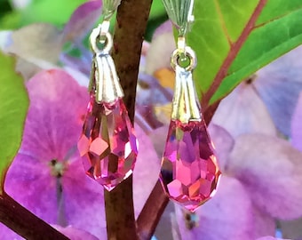 May include: A pair of silver dangle earrings with pink teardrop-shaped crystals hanging from the bottom.